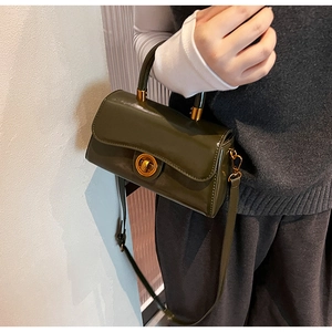 Detail of vintage dark green leather handbag featuring a golden round metal turn-lock