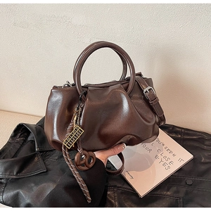 Gros plan du sac seau plissé marron vintage avec breloque dorée sur cuir noir