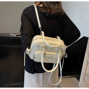 Detail of a beige bowling bag with dual zippers and adjustable strap shown on a model