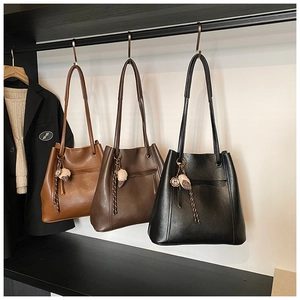 Tre borse tote in pelle nei colori marrone, caffè e nero con nappe sull'appendiabiti