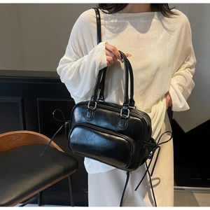 Detail of black leather bowling bag with front zipper pocket and adjustable strap