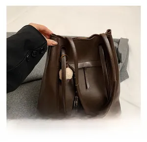 Dettaglio della borsa tote in pelle testa di moro con pompon decorativo e cinturini