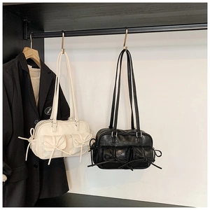 Detail of cream and black chic bow backpacks with micro-wrinkle leather hanging in a closet