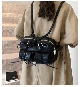 Rear view of a black multi-pocket backpack worn over a trench coat on stairs
