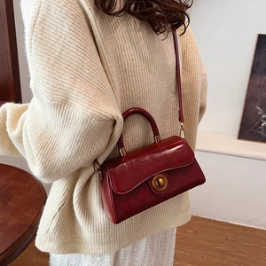 Vintage burgundy patent leather handbag with gold ring lock shown on cream sweater outfit