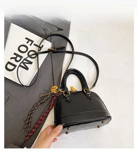 Detail view of black leather handbag with golden hardware and heart charm attachment