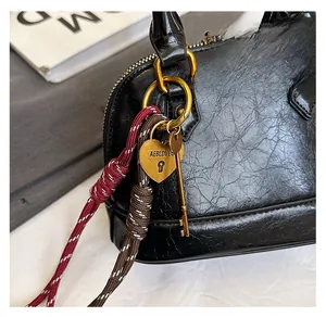 Detailed close-up of a black textured shell bag with golden heart lock and key charms
