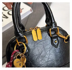 Detailed close-up of smooth gold double zippers and engraved heart lock on black shell bag