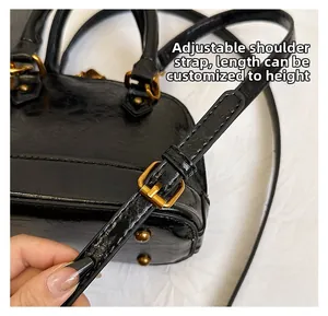 Detail of adjustable shoulder strap with gold buckle on black oil wax leather bag