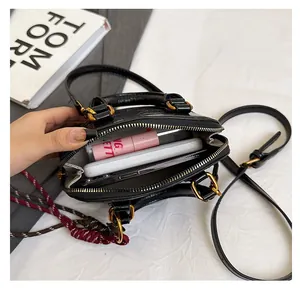 Interior view of black croc-effect handbag showing space for phone and lipstick