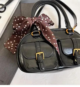 Close-up of glossy black bowling bag with gold hardware and a polka dot silk scarf