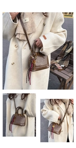 Detail view of dark brown shell-shaped crossbody bag with gold hardware and ribbon charm