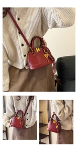 Detail of burgundy shell bag with golden heart lock pendant and dual zipper hardware