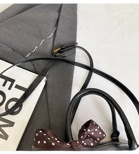 Detail of black bowling bag with adjustable shoulder strap and decorative silk scarf