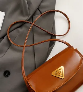 Detail of a brown leather bag showing the golden triangular logo and textured wax finish