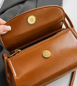Close-up of brown textured crossbody bag showing gold magnetic closure and hardware
