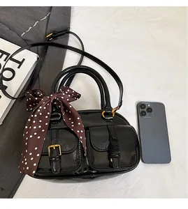 Chic black bowling bag with front flap pockets and polka dot scarf on light background