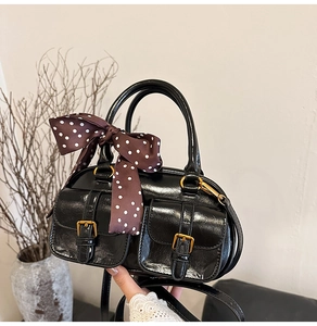 Detail of black bowling bag with decorative ribbon and gold buckles in lifestyle setting