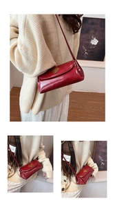 Macro detail of red oil-wax leather pillow bag with gold triangle plaque and strap