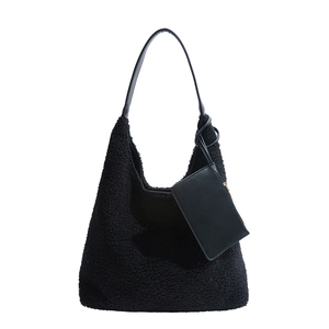 Borsa a spalla in peluche nera con pochette in pelle abbinata su sfondo bianco puro