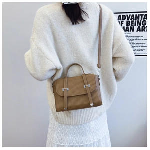 Detail of caramel brown crossbody bag with pleated texture and silver metal buckles