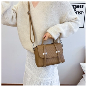 Detailed view of brown pleated crossbody bag with silver buckle and leather strap