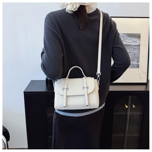 Cream crossbody bag with vertical pleated texture and silver hardware on a female model