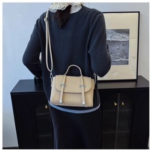 Vertical textured leather crossbody bag with silver buckle worn by a model in a minimal setting