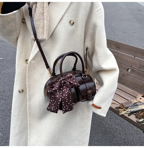 Detail of dark coffee brown vintage bowling bag with a polka dot scarf and shoulder strap