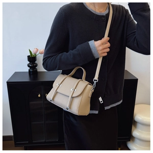 Detailed view of beige faux leather handbag featuring vertical textures and silver metal buckles