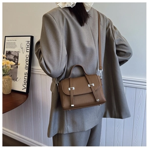 Close-up of brown vertical textured leather crossbody bag with silver buckle detail