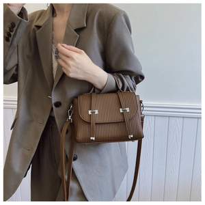 Detail of dark brown crossbody bag featuring vertical striped embossing and silver hardware