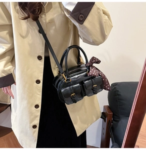 Detail of a black leather bowling bag with silk scarf on a beige trench coat