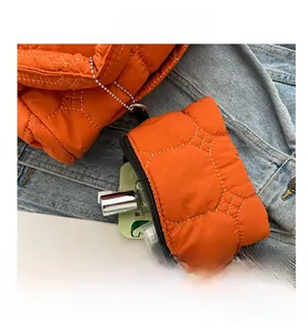 Macro shot of quilted bright orange down nylon mini pouch with black zipper detail