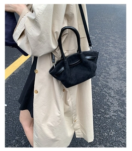 Close-up of black suede and leather mixed bag with a curved silhouette and handle