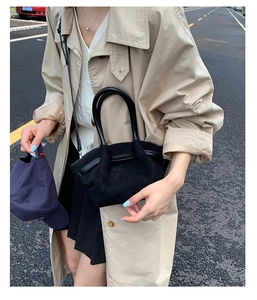 Street style shot of a black pleated tote bag with round handles and suede texture
