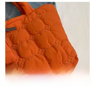 Macro shot of orange quilted puffer tote bag fabric with hexagonal stitching details