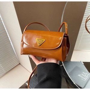 Detailed shot of brown faux leather crossbody bag featuring a golden triangle emblem