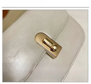 Dettaglio della chiusura a scatto dorata e pelle martellata su borsa bianco avorio