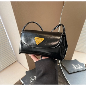 Detail of glossy black wax leather pillow bag featuring a yellow triangle logo