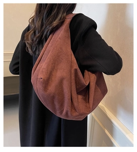 Grand sac fourre-tout en daim mat rouge brique porté avec un manteau noir élégant