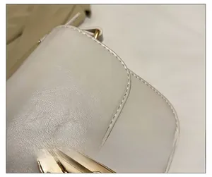 Dettaglio macro con cuciture precise su pelle crema e chiusura in metallo dorato