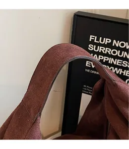Gros plan sur les poignées larges et la texture en daim doux du sac cabas marron