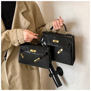 Sac à main classique en cuir verni noir avec quincaillerie dorée style rétro élégant.