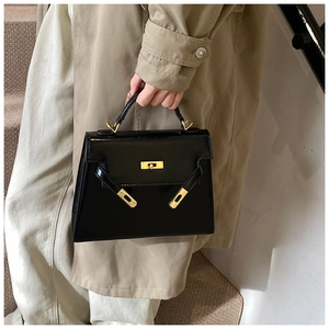 Sac à main noir classique pour femme, style Kelly vintage avec poignée supérieure et détails dorés.
