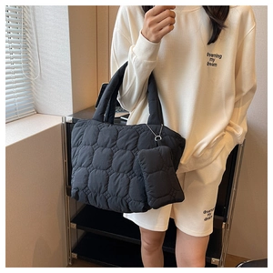 Detail of black quilted tote bag with matching small pouch on a metal chain