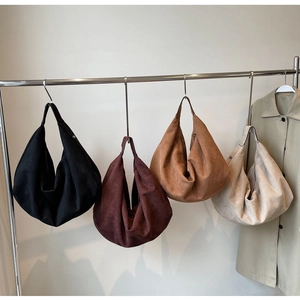 Détails de sacs cabas en daim en noir, bordeaux, caramel et beige sur un présentoir