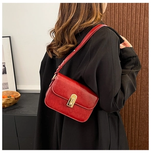Dettaglio borsa vintage rossa in pelle con fibbia dorata su un cappotto nero