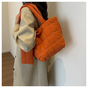 Detail of orange quilted puffer tote bag and matching scarf set in glossy nylon