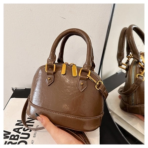 Detail view of brown shell bag in vintage cracked PU leather with gold hardware